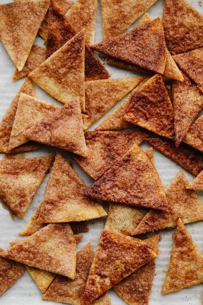 Baked cinnamon sugar tortilla chips laid out on a pan.