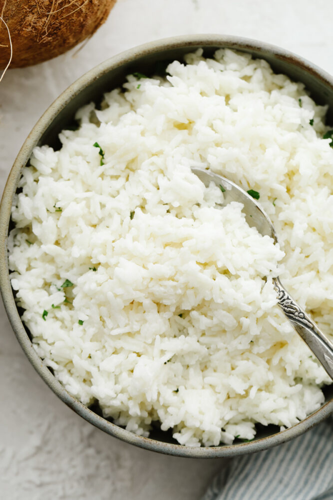 Coconut rice in a bowl with cilantro and a spoon. 