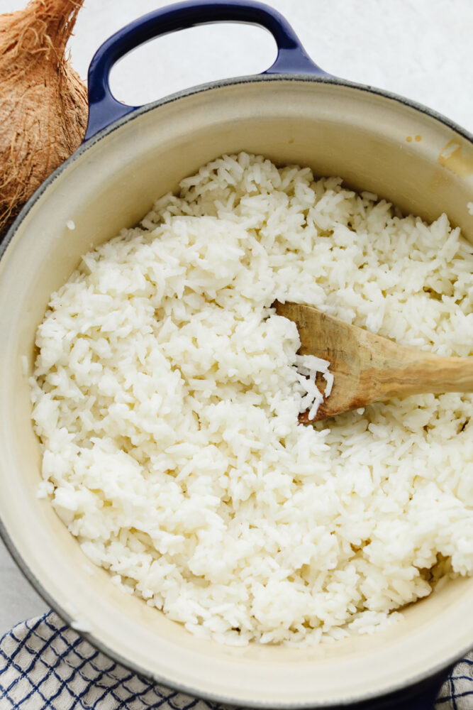 Coconut rice in a bowl with a wooden spoon.