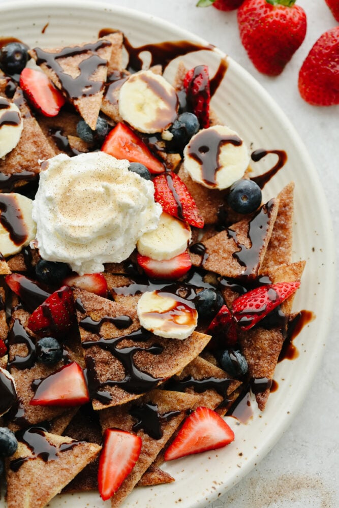 A plate of dessert nachos tipped with whipped cream. 