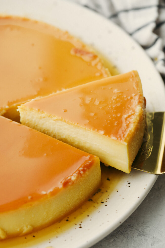 Flan sliced and a slice being taken from the cake. 