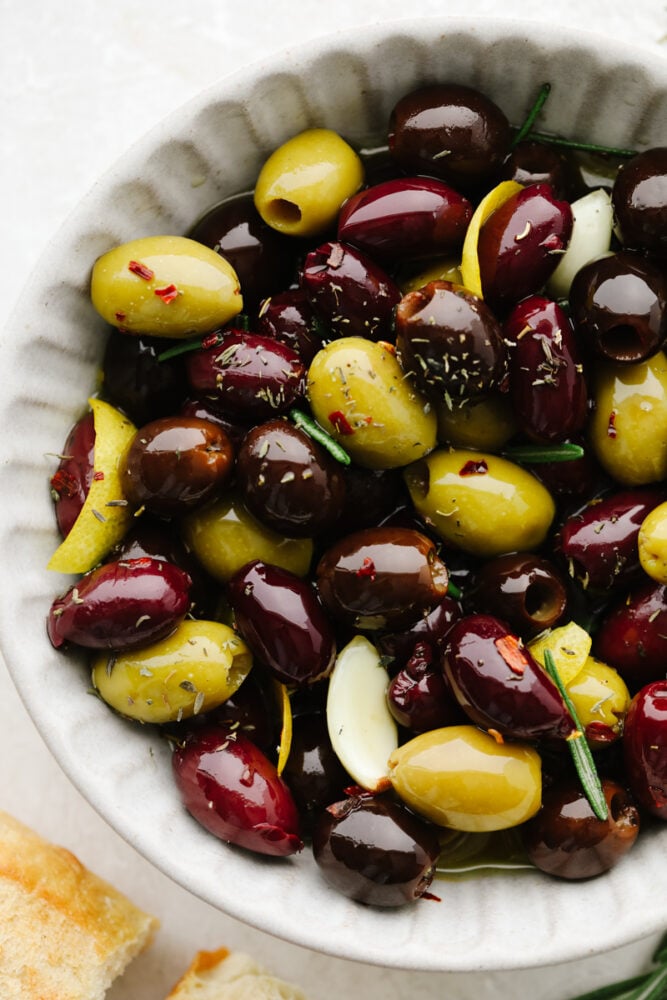 Closeup of seasoned olives in a white bowl.