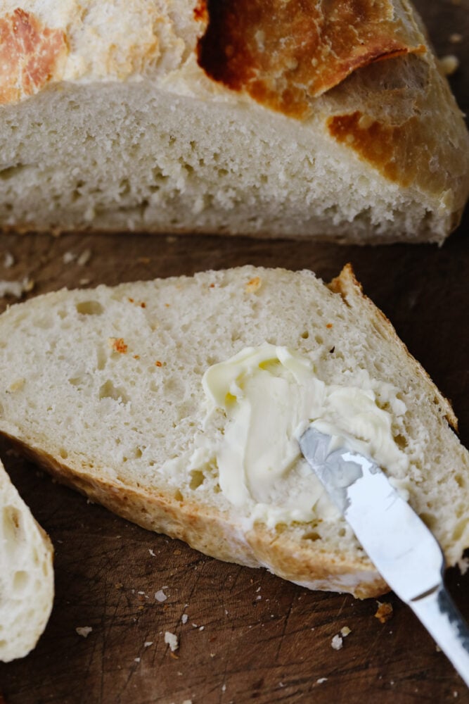 A knife spreading butter onto a slice of bread.
