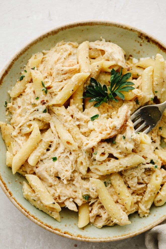 Chicken and pasta on a plate with a fork. 