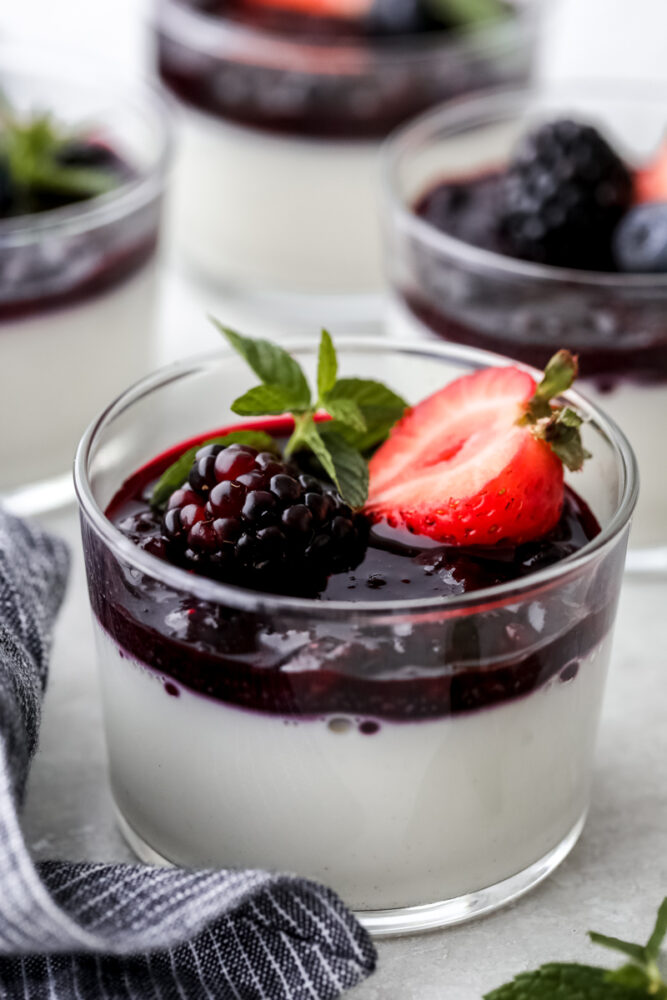 Panna cotta in a glass cup garnished with berries. 