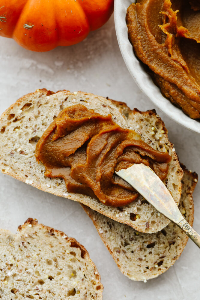 Pumpkin butter being spread on toast with a butter knife. 
