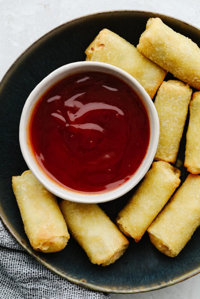 A platter with egg rolls and sweet and sour sauce. 