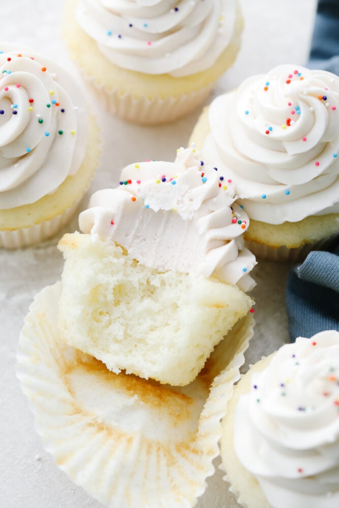 A white cupcake with a bite taken out of it. 