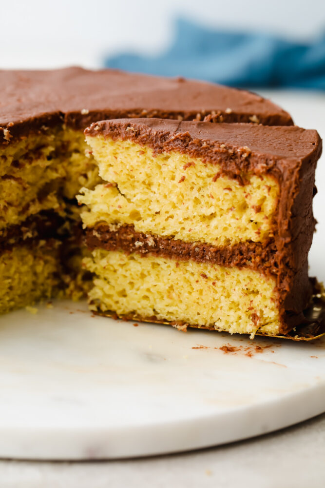 Yellow cake with chocolate frosting with a slice being pulled out. 