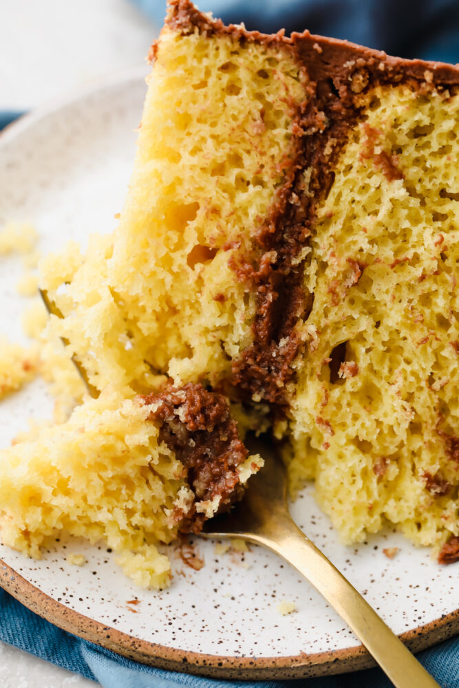 Een plakje gele cake met een vork die er een hap uit neemt. 