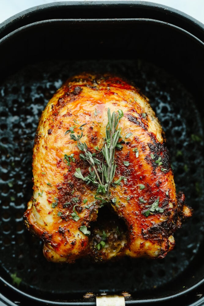A turkey in an air fryer with garnish. 