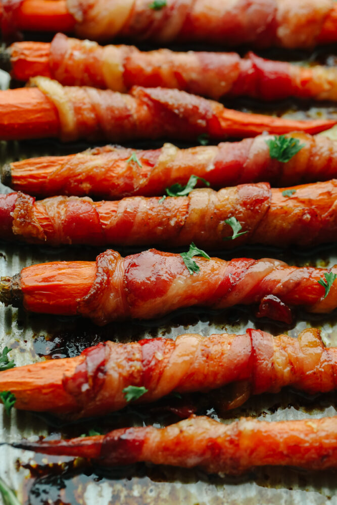 Closeup of bacon-wrapped, honey-glazed carrots garnished with parsley.