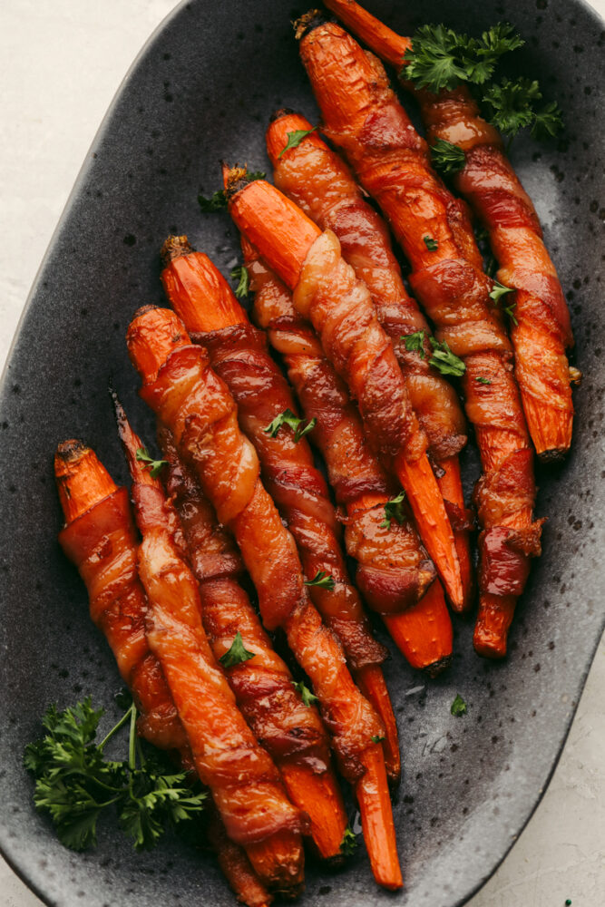 Bacon-wrapped carrots in a stoneware serving dish.