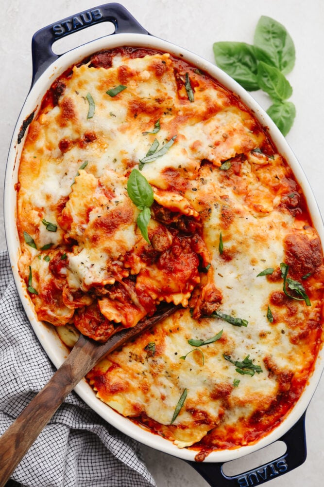 Baked ravioli in a casserole dish, garnished with basil. 