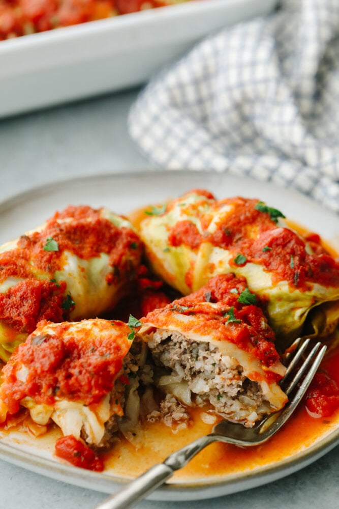 A cabbage roll on a plate with a fork cutting into one. 