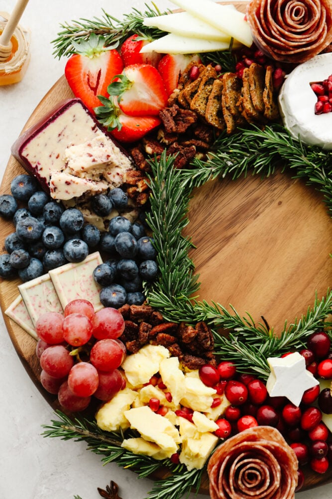 A close up of the side of the Christmas wreath charcuterie board. Grapes, cheese, pecans, cranberries and blueberries. 