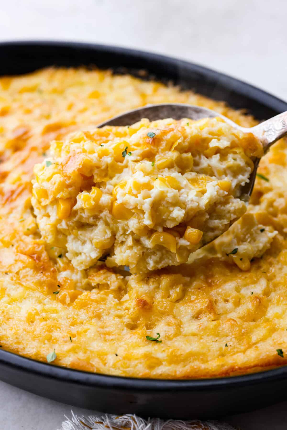 Close up shot of corn pudding in a serving spoon. 