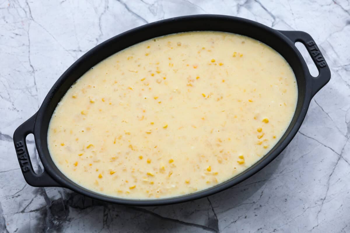 Overhead shot of corn pudding ingredients in a baking dish ready to go in the oven. 