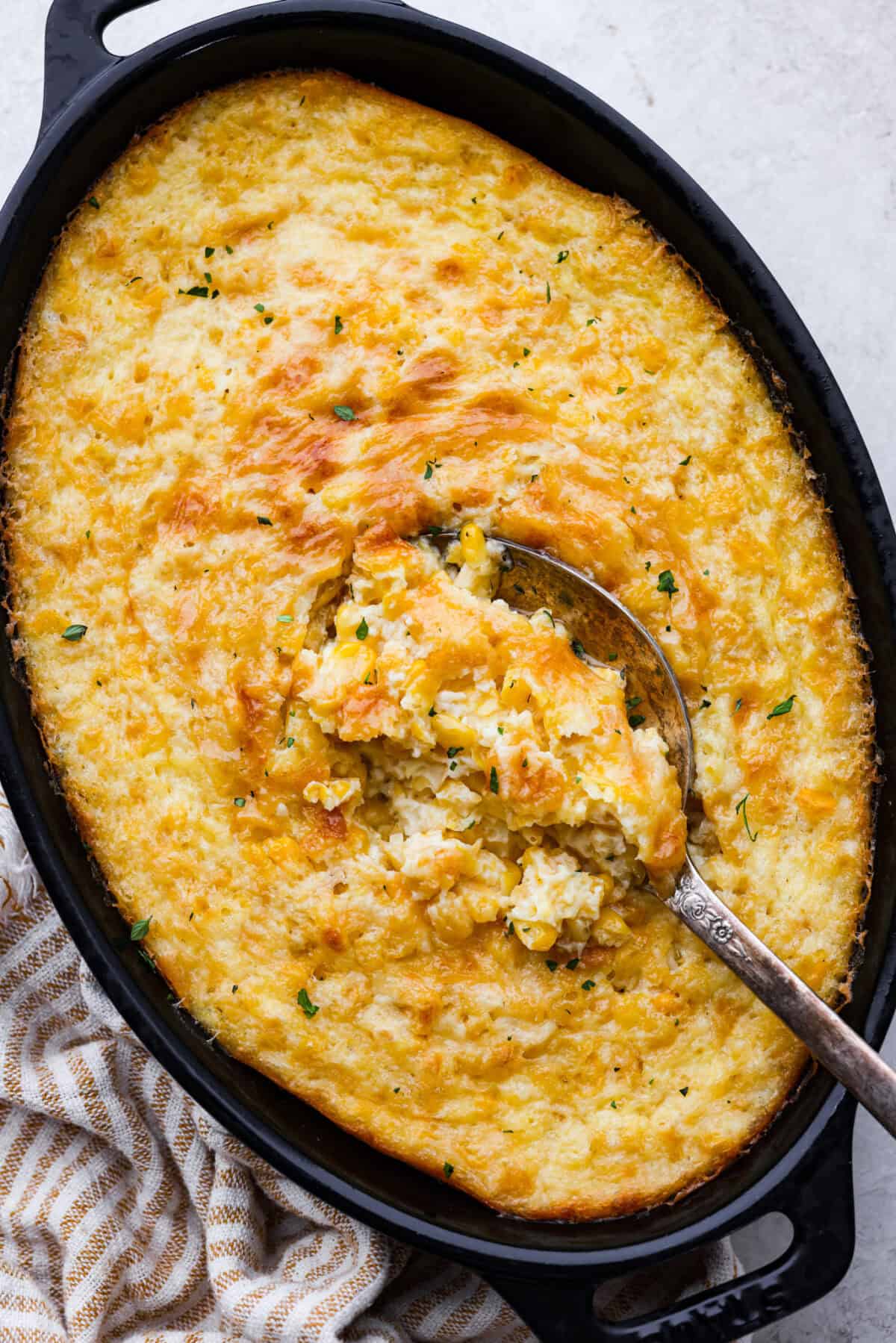 Overhead shot of corn pudding in a baking dish with a serving spoon in it. 