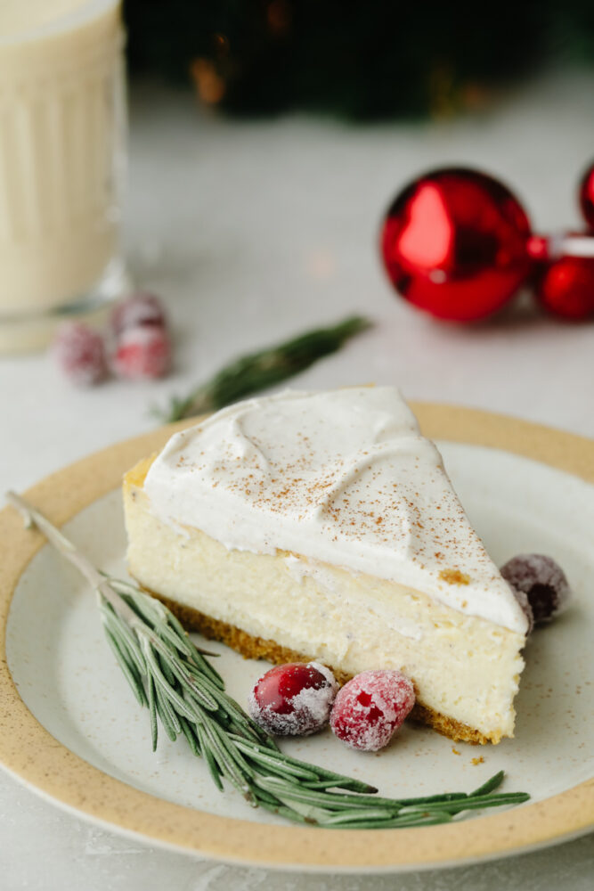 A slice of cheesecake on a plate with sugared cranberries.  