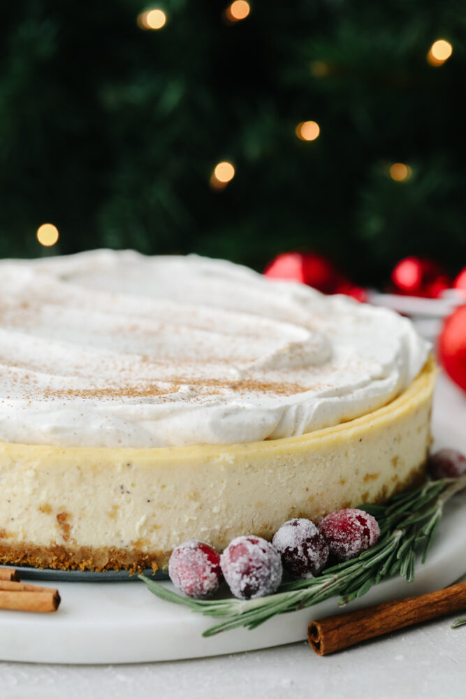 A zoomed in view of the side of a whole eggnog cheesecake. 