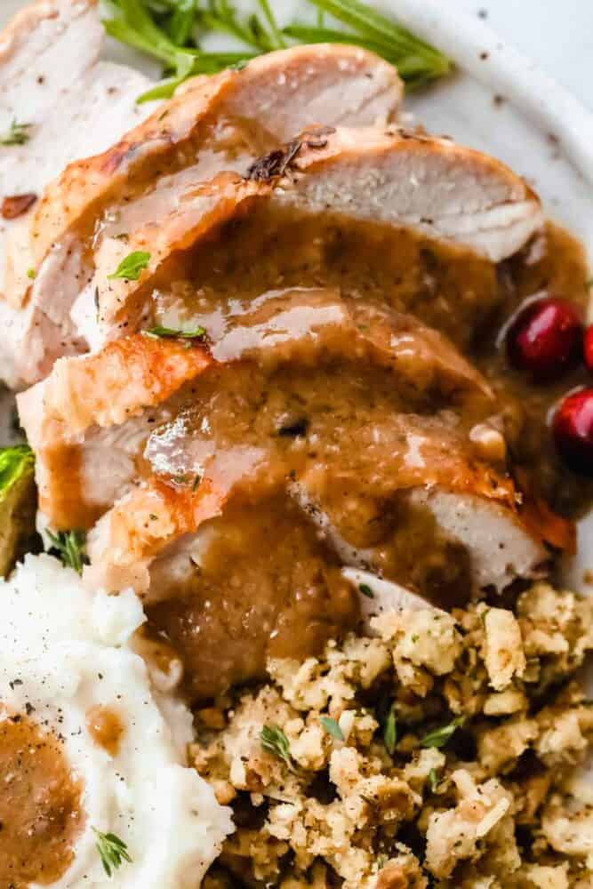 Gravy on top of turkey, potatoes and stuffing on a plate. 