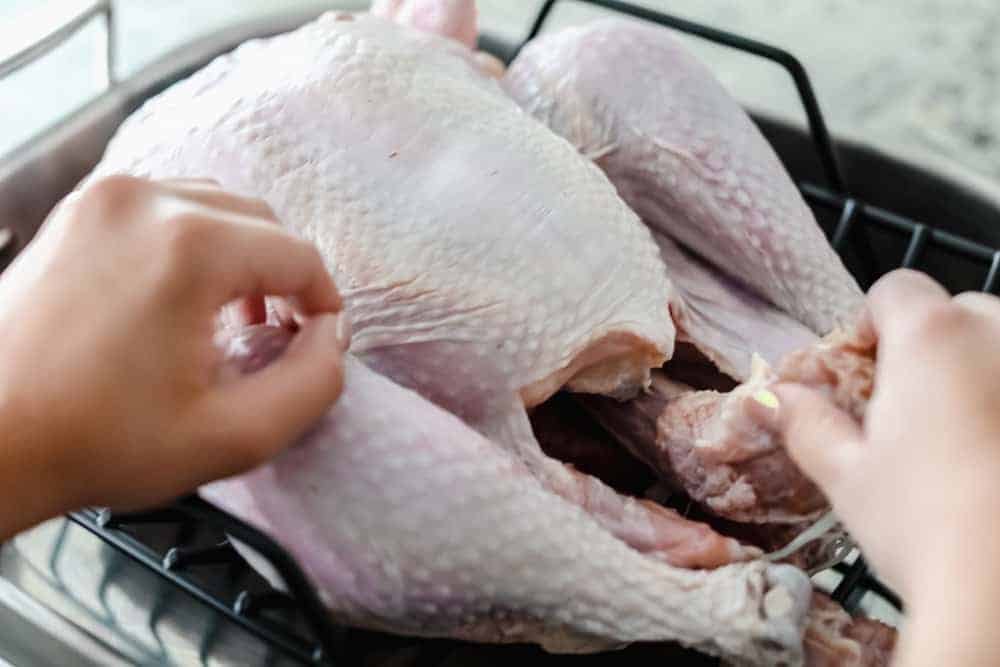 A picture of how to remove the giblets from a raw turkey. 