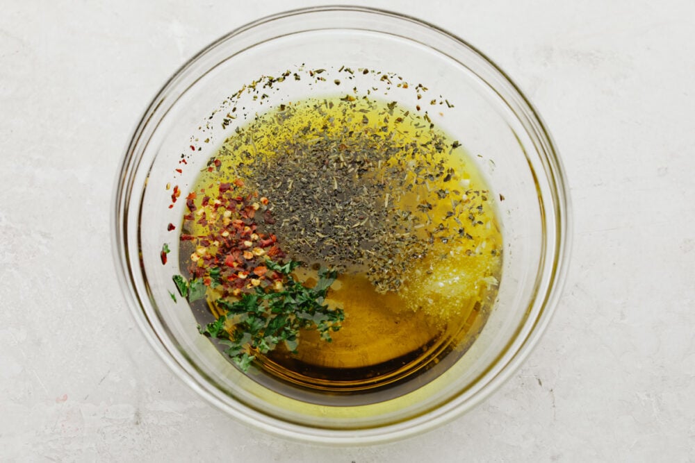 a bowl with olive oil and spices being mixed into it. 