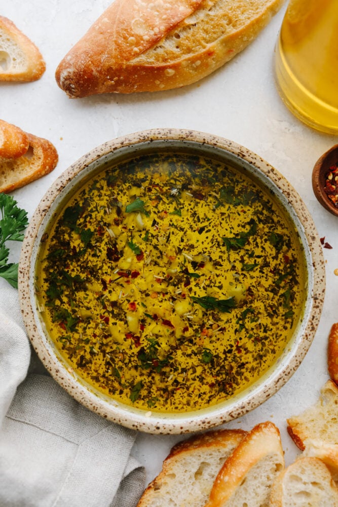 A bowl of olive oil dip with bread next to it. 