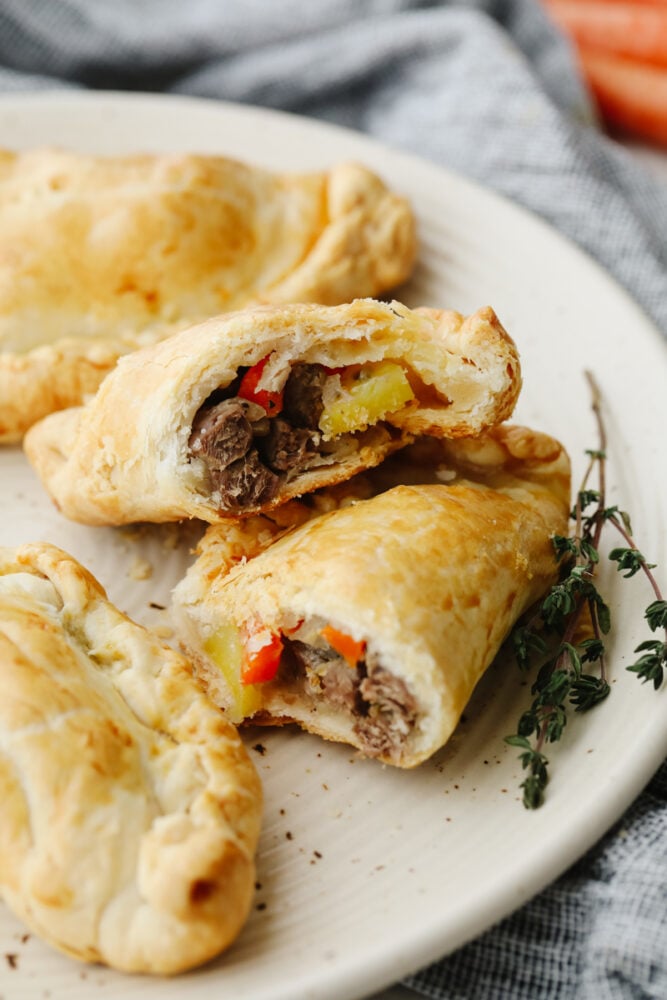Cornish pasties on a plate cut open so that you can see the meat and veggies inside. 
