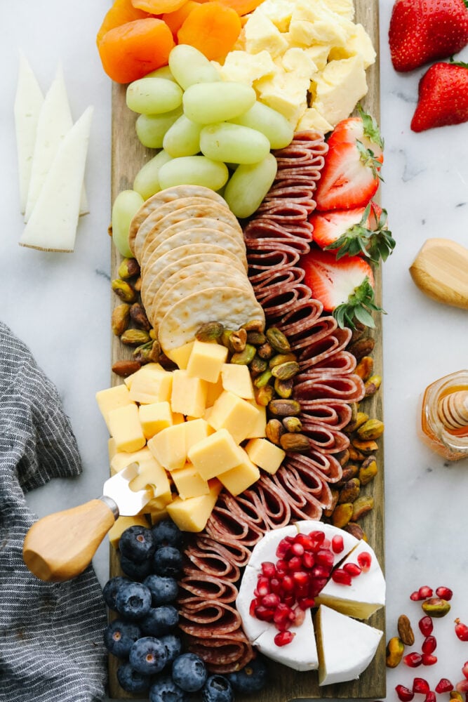 A simple charcuterie board filled with fruits, crackers, nuts and meats. 