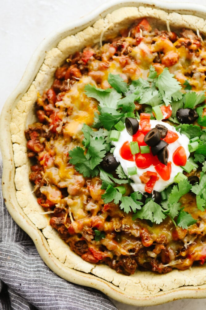 A taco pie garnished with toppings. 