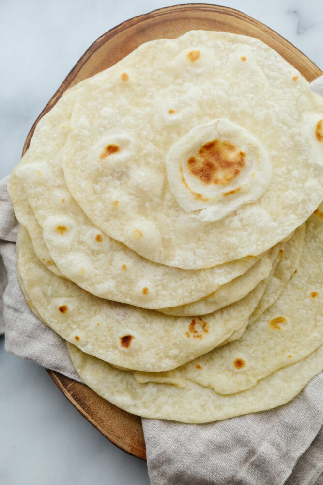 A stack of homemade tortillas on a platter. 