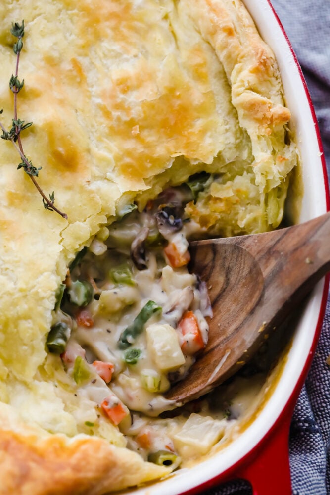 Closeup of scooping up vegetarian pot pie with a wooden spoon.
