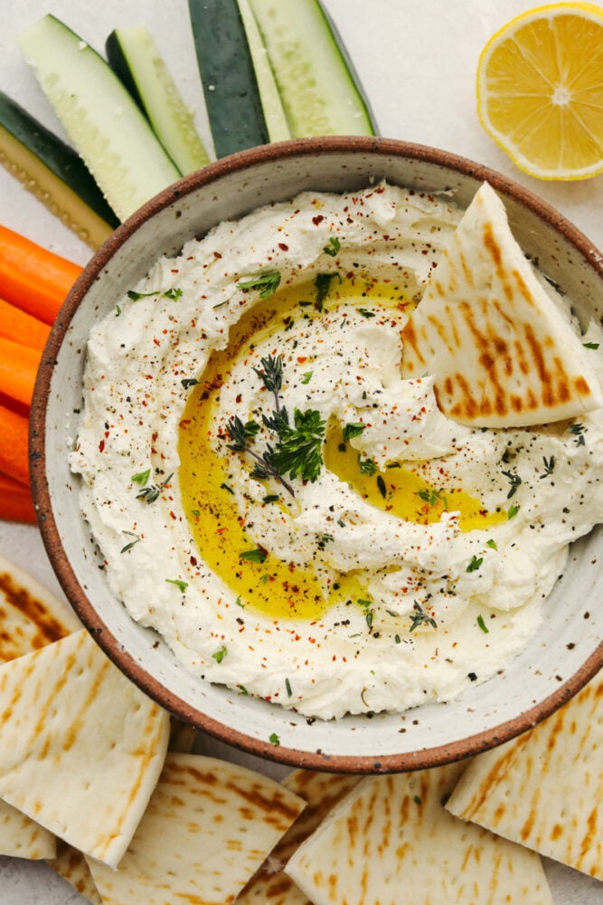 Whipped feta dip in a bowl with a pita slice in it. 