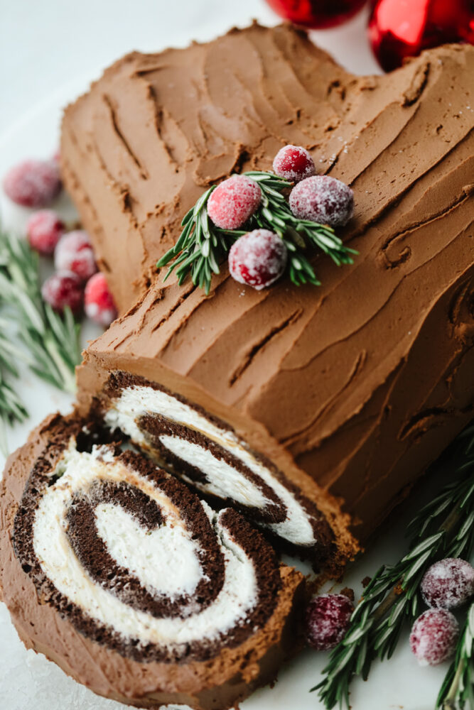 A yule log cake with a slice showing the inside swirl. 