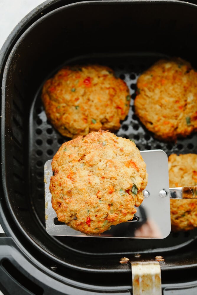 4 crab cakes in the basket of an air fryer.