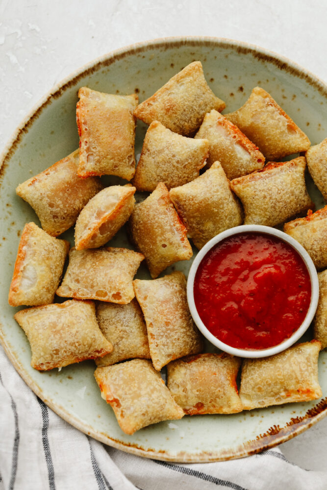 Pizza rolls on a plate with marinara sauce. 