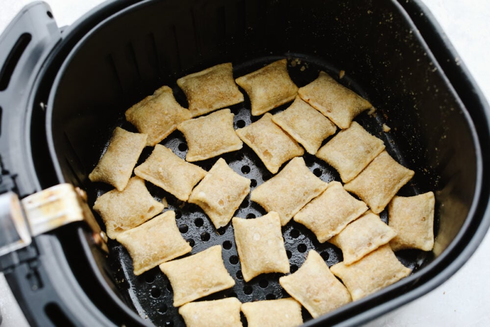 Frozen pizza rolls in an air fryer basket about to be cooked. 