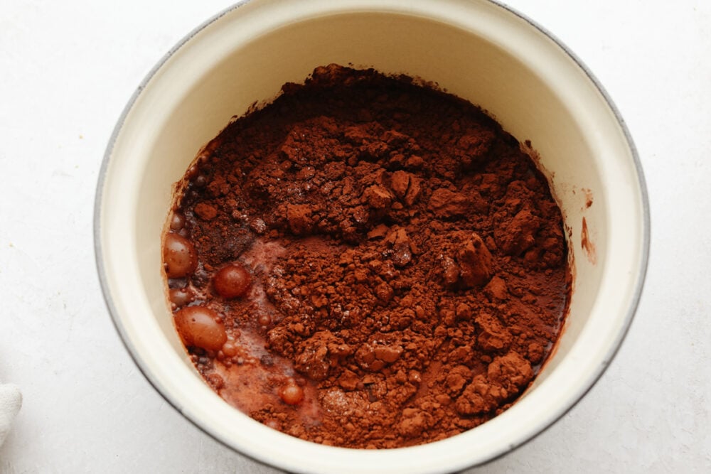 A bowl of cocoa powder being mixed with milk.