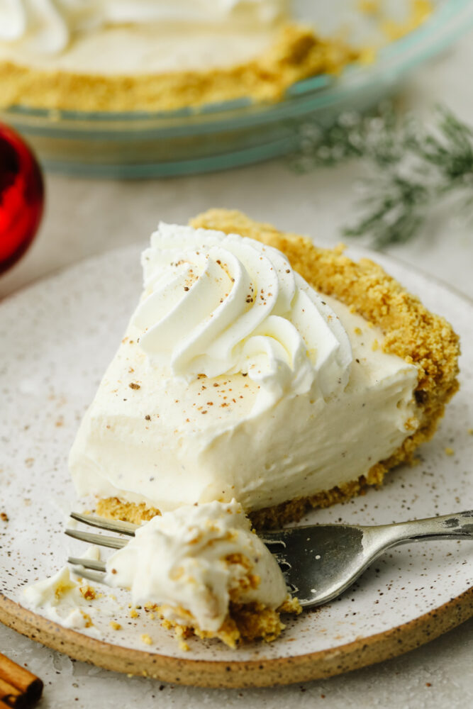 A slice of eggnog pie on a plate with a fork cutting into it. 