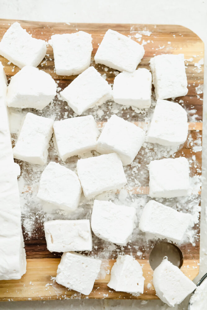 Homemade marshmallows on a wooden cutting board.