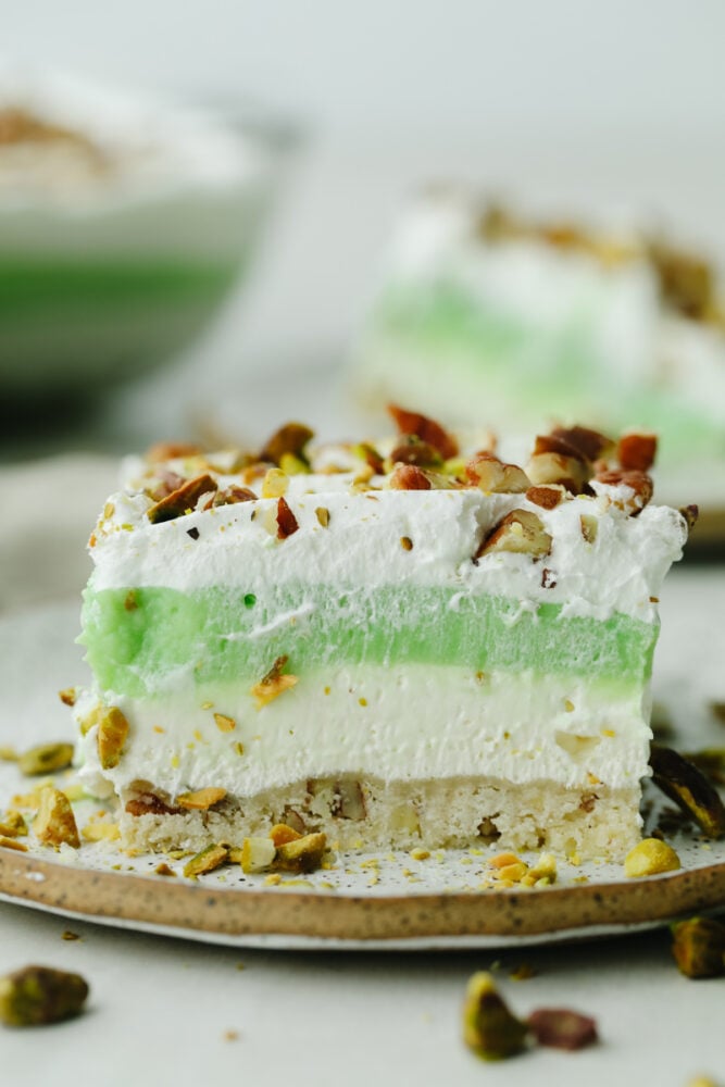 A slice of layered pistachio dessert on a plate. 