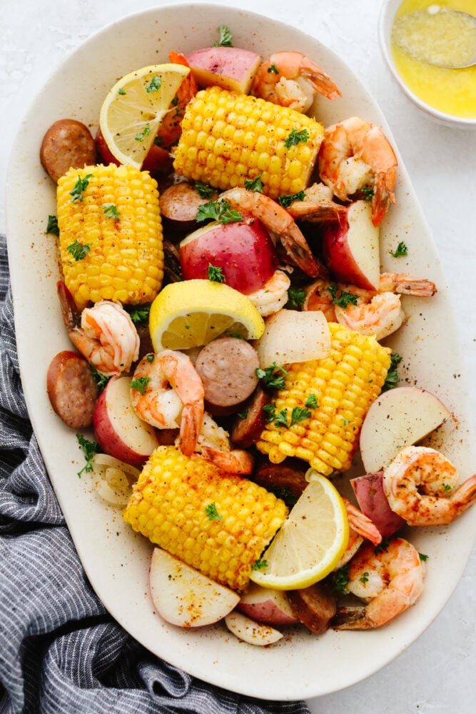 A southern classic, this shrimp boil recipe includes corn, potatoes, sausage, and shrimp boiled together in one pot and packed full of delicious flavor! It's a tried and true favorite that you don't want to miss! Shrimp boil ingredients on a serving platter.