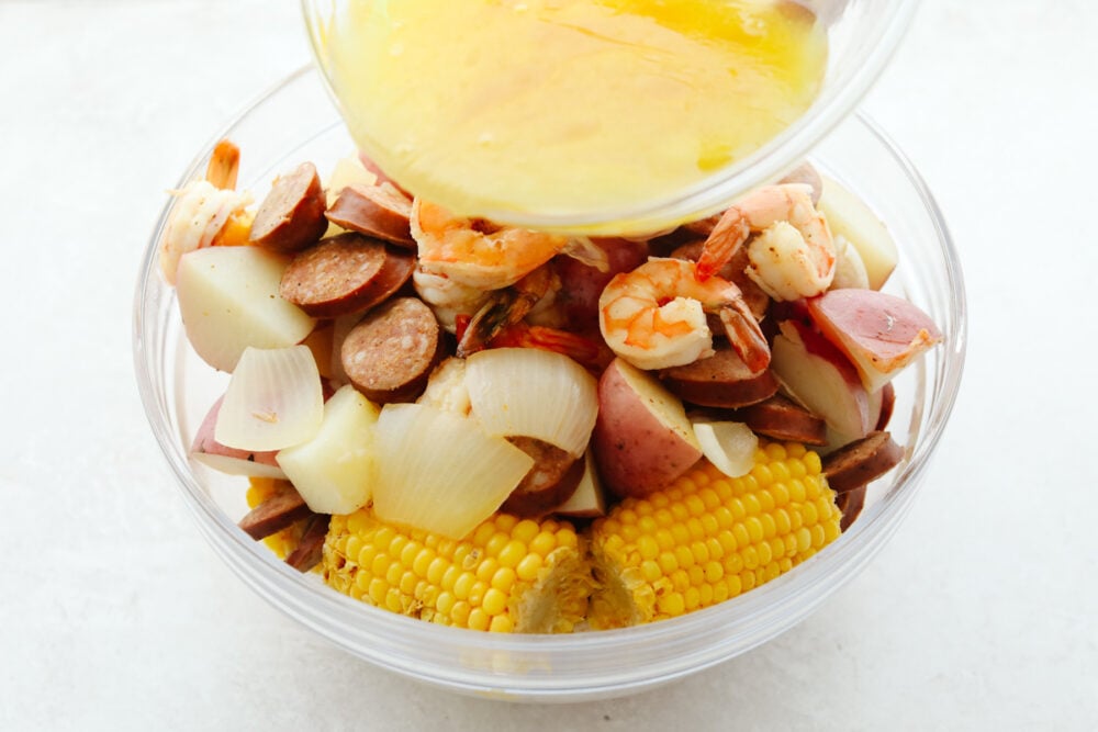 Melted butter being poured onto ingredients in a bowl. 