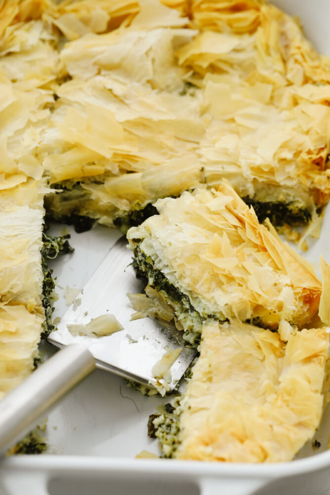 Slices of spanakopita on a dish being dished up. 
