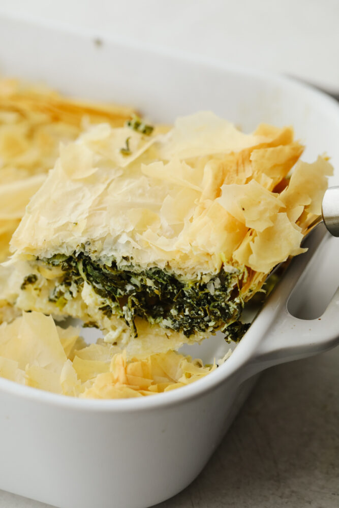 A slice of spanakopita in a dish being served. 