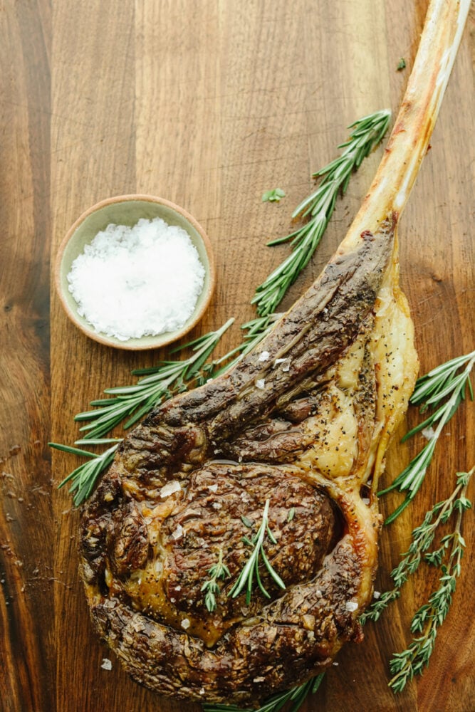 A tomahawk steak with garnish on a cutting board. 