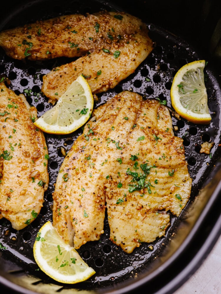 Cooked Cajun tilapia in the basket of an air fryer.