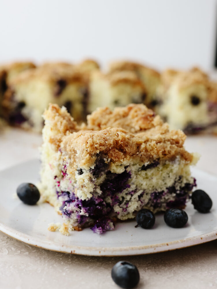 A slice of blueberry buckle on a white plate.